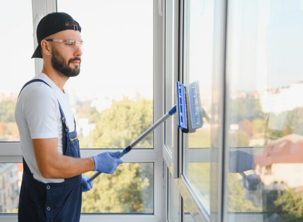 An employee of a professional cleaning service washes the glass of the windows of the building. Showcase cleaning for shops and businesses.